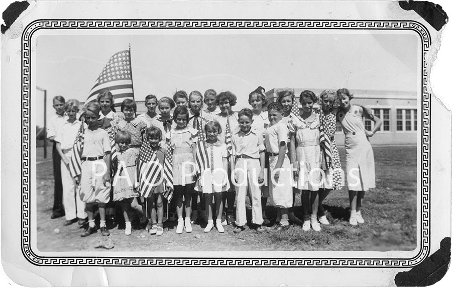 Vintage photo of group of students assembled in front of U.S. flag